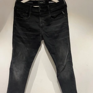 Replay Anbass svarta jeans, W31 L30 - Svarta Replay Anbass jeans med slim passform och klassisk femficksdesign. Jeansen har svarta sömmar, diskret Replay-logga på fickan och är tillverkade i stretchigt jeansmaterial för skön komfort. Perfekt för dig som gillar en modern och stilren look.