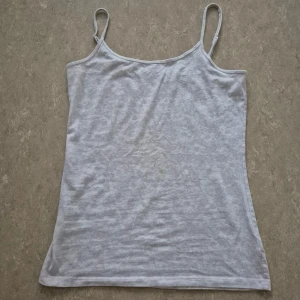 Linnetopp - Säljer en enkel och stilren vit linnetopp från Nollie i storlek S. Toppen har smala axelband och ärmlös design, perfekt för varma dagar. Materialet är mjukt och lätt bomull som känns skönt mot huden. Passformen är normal och toppen har en klassisk rak form.