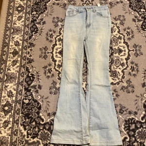 Bootcut ljusblå jeans från SHEIN XS - Snygga ljusblå bootcut jeans från SHEIN i storlek XS. Klassisk femficksmodell med hög midja och utsvängda ben. Jeansen är tillverkade i bomull och polyester, vilket gör dem både bekväma och slitstarka. Perfekta för dig som gillar retrovibbar och en avslappnad stil.