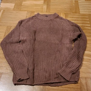 Brun stickad tröja från 157, XS - Säljer en brun stickad tröja från 157 i storlek XS. Tröjan har en ribbad hög hals och grovstickad struktur som ger en chill och avslappnad vibe. Långa ärmar med ribbade muddar och en loose passform. Perfekt för dig som gillar enkla och snygga plagg.