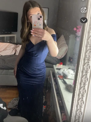 Marinblå långklänning offshoulder - Säljer en elegant marinblå långklänning med offshoulder och v-ringad omlottdesign. Klänningen har figurnära passform och passar perfekt till firande❤️