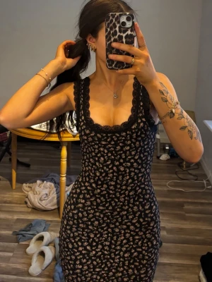 Svart blommig kortklänning med spets -  Figurnära passform som framhäver siluetten, perfekt för sommardagar. Den slutar där bilden slutar. 