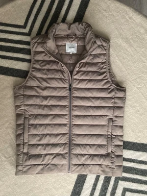 Dunväst från Jack & jones - Säljer en beige dunväst från Jack & Jones. Den är en storlek S men stor i modellen och passar M istället.
