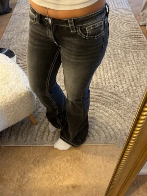 Svarta bootcut jeans  - Säljer ett par svarta bootcut jeans med tydliga vita kontrastsömmar och låg midja. Dom är ifrån Gina Young💗 aldrig använda, innebenslängd 100 cm.  Midjemått 39,5 cm