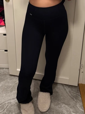 Black Ribbed Seamless Flare Tights - Säljer ett par svarta ribbade Aimin leggings med bootcut-modell och hög midja. De är stretchiga och sitter tajt upptill men släpper vid vaden för en snygg siluett. Materialet är mjukt och följsamt, vilket gör dem riktigt bekväma. Aldrig använda, köpta för 700 kr