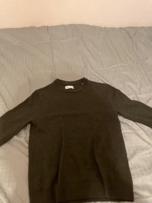 Mörkgrön stickad tröja från These glory days  - En stilren mörkgrön stickad tröja från these glory days. Tröjan har rund halsringning och långa ärmar, perfekt för lager-på-lager under kyliga dagar. Enkel och klassisk design som funkar till det mesta. Materialet är mjukt och skönt mot huden.