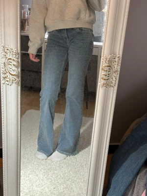 Blå bootcut jeans från H&M, strl 34 - Säljer ett par klassiska blå bootcut jeans från H&M i storlek 34. Jeansen har en snygg midwaist passform och är tillverkade i mjukt denimtyg med fickor.