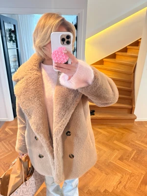 Beige teddyjacka med stora slag - Supermjuk och fluffig teddyjacka i beige med stora slag och dubbelknäppning framtill. Jackan har en oversized passform och är perfekt för kyliga dagar. Den har långa ärmar och en stilren look som är lätt att matcha med olika outfits.