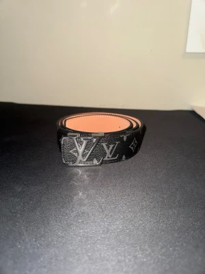 Designerbälte – svart monogram med matt svart spänne - Stilrent svart designerbälte med klassiskt monogrammönster och matt svart metallspänne. Clean och tidlös design som passar perfekt till både jeans och kostymbyxor. Hög kvalitet och snygga detaljer.  ✔ Mycket fint skick ✔ Slitstarkt material ✔ Justerbar längd ✔ Unisex  Perfekt accessoar som lyfter outfiten. Skriv vid frågor 🔥