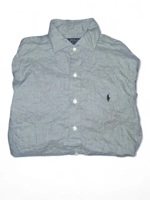 Grå skjorta från Polo Ralph Lauren - Snygg grå skjorta från Polo Ralph Lauren i slim fit-modell. Klassisk krage, långa ärmar och knäppning framtill. Ikoniska broderade loggan på bröstet. Tillverkad i mjuk bomull som känns skön mot huden.