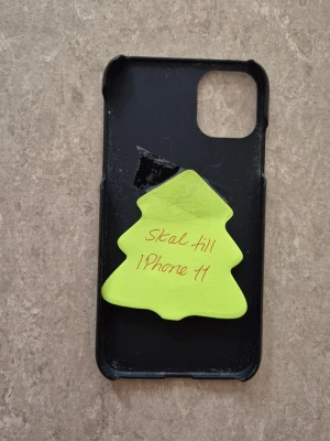 Mobilskal - Elegant svart mobilskal från iDeal of Sweden, anpassat för iPhone 11. Skalet har viss yttre slitage men är i gott skick och skyddar din telefon effektivt. Perfekt passform och stilren design.