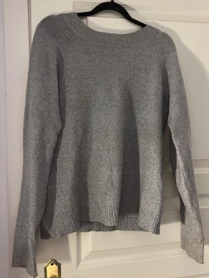 Grå stickad tröja med rund hals - En enkel och stilren grå stickad tröja med rund halsringning. Tröjan har långa ärmar och ribbade muddar vid ärmslut och nederkant. Perfekt att matcha med jeans för en chill look.