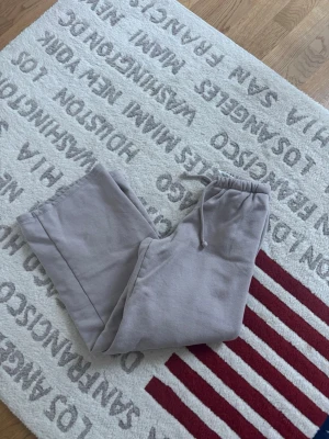 Beige mjukisbyxor från H&M XXS - Superbekväma beige mjukisbyxor från H&M i storlek XXS. Vida ben och elastisk midja med dragsko för perfekt passform. Tillverkade i en mjuk bomulls- och polyestermix som känns skön mot huden. Perfekta för chill dagar eller när du vill vara extra comfy.