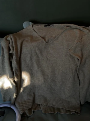 Grön v-ringad stickad tröja S - Mysig grön stickad tröja från Gina Tricot i storlek S. Tröjan har v-ringning och långa ärmar, perfekt för lager på lager under kyliga dagar. Ribbstickade muddar vid ärmslut och nederkant ger en snygg finish.