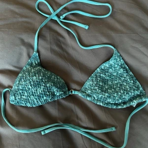 Turkos bikini topp - Säljer en turkos trekantsbikini med knytband i nacken och ryggen. Bikinin har en snygg strukturerad yta som ger en unik look. Perfekt för strandhäng eller pooldagar. Helt oanvänd 