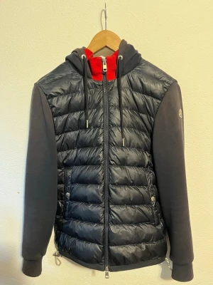 Moncler cardigan - Säljer en mörkblå cardigan från Moncler som fortfarande är i hyfsat bra skick. Storlek M men sitter som en S. Har tyvärr inget kvitto och låda kvar. Skriv om ni har några frågor. Kom med bud.