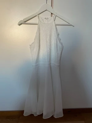 Vit spetsklänning med chiffongkjol - Supersöt vit studentklänning från Nelly med spets upptill och flowy chiffongkjol. Den har kommit till användning ENDAST en gång på min student, därför skulle jag säga att den är som nyskick. Klänningen har hög halsringning och är ärmlös, med dragkedja i ryggen. Perfekt till student eller sommarens alla tillfällen!