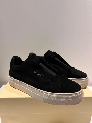 Svarta sneakers från Axel Arigato - Säljer mina Axel Arigato i mocka. Märket på vänster sko är lite slitet, se bild. De kommer ny sprejade och i sin orginalförpackning 