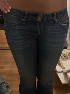 Blå lågmidjade bootcut jeans - Säljer ett par klassiska blå Levi's jeans utsydda i bootcut-modell. Jeansen har låg midja, med snygga slitningar och tvättade detaljer.