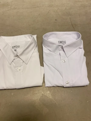 2st Vita Skjortor, kort ärmade - Säljer 2 kortärmade skjortor från Smog i storlek M. Köpta på New Yorker för 150kr styck och jag säljer båda för 100kr, så du sparar 66%/200kr. Skjortorna är sparsamt använda och har inga defekter. Skriv vid frågor eller intresse🌟🌟🌟
