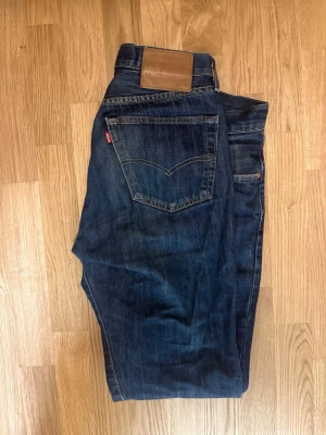 Levi's 501  - Klassiska Levi's 501 jeans i mörkblå tvätt med raka ben och femficksmodell. Snygga kontrastsömmar och ikonisk läderpatch bak i midjan. Tillverkade i slitstarkt bomullsjeans. Perfekta för dig som gillar tidlös och avslappnad stil.