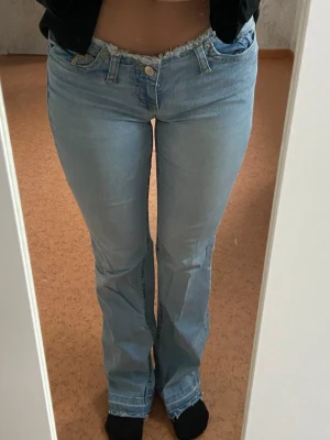 Bootcut jeans med fransad midja från Nelly - Bootcut jeans i ljusblå tvätt från Nelly med låg midja och rå, fransad kant upptill. Snyggt utsvängda ben och trendig, avslappnad look🩵