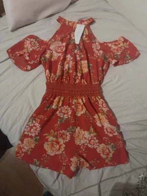 Jumpsuit/ overall med shorts - Röd blommig jumpsuit med smockad midja. Bekväm passform med stretch i midjan.