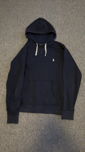 Ralph Lauren hoodie - Säljer en riktigt fet hoodie från Ralph Lauren. Marinblå färg med vit logga och vita snören som ger en stilren look. Hoodien är i extremt bra skick 10/10 och har inga defekter. Bara att höra av sig vid minsta fundering! 🙌