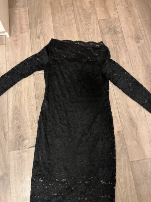 Svart spetsklänning från Vila - Säljer en svart långärmad spetsklänning från Vila. Klänningen har ett blommigt spetsmönster, är figurnära och har en klassisk, elegant look. Perfekt för dig som vill ha något stilrent och snyggt. 