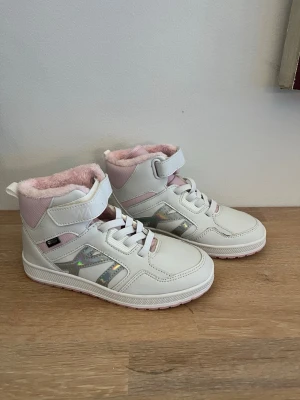 Vita/rosa sneakers - Säljer ett par sprillans nya höga sneakers från WARP i vitt och ljusrosa med glansiga detaljer på sidan som aldrig har använts. Skorna har snörning, kardborreband och fluffigt rosa foder. Perfekta för dig som vill ha både stil och värme under kalla dagar. || Orginalpris: 500 || Mitt pris: 200 ||