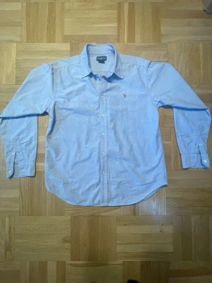 Ljusblå skjorta från Ralph Lauren - Klassisk ljusblå skjorta från Ralph Lauren med broderad logga på bröstet. Runt XS S men jag kan skicka mått om det behövs.
