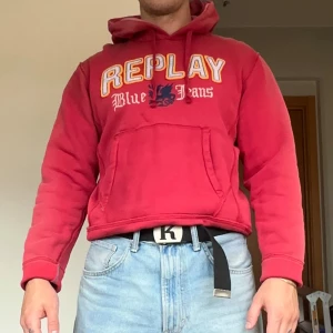 Röd vintage hoodie från Replay - Säljer en röd hoodie från Replay med broderat och tryckt logga på bröstet. Tröjan har huva med snörning, magficka och långa ärmar. Mjuk insida i bomullsmix, perfekt för chill dagar. Klassisk streetwear-vibe och snygg passform. Sitter som en S/M