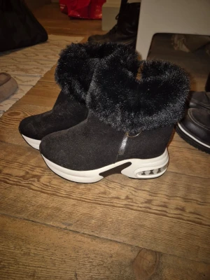 Svarta ankelboots  - Svarta boots med fluffig fuskpäls runt skaftet och vit platåsula. Skorna har dragkedja på sidan och materialet är mockaliknande och insidan är mjuk. Fint skick, storlek 43💓