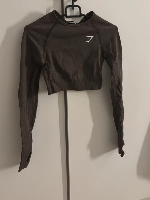 Gymshark Träningstopp  - En croppad träningstopp av Gymshark i storlek XS. Väldigt stretchig, passar storlek S också. I färgen mocka brun. Gåva vid köp!🎁