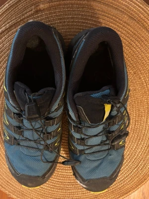 Salomon XA Pro blå/gula sneakers - Salomon XA Pro sneakers i blått med svarta och gula detaljer. Skorna har snabbsnörning och robust sula med bra grepp. Ovandelen är i mesh och syntet, perfekt för dig som gillar att vara aktiv utomhus. Väldigt gott skick! 