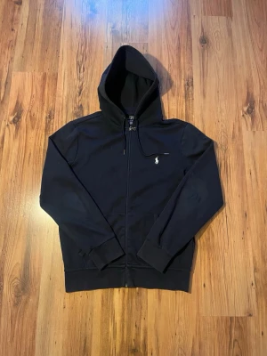 Navy double knit Ralph Lauren zip hoodie  - Marinblå Ralph Lauren zip hoodie 🏇🏽 Size S/170, mått ⤵️                                                            📏 Längd (Axel till mudd) - 65 cm Bröstbredd - 49 cm  Ärmlängd - 63 cm                              8/10 skick, äkta, mycket fräsch, bara några skrapmärken på ena ärmen                                Hör av er om ni har frågor 😎