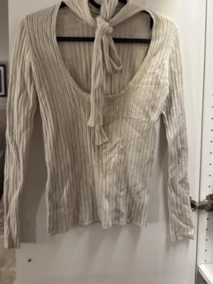Ribbad beige tröja med öppning i ryggen Gina Tricot - Supersnygg ribbad beige tröja från Gina Tricot i storlek XS. Tröjan har lång ärm, poloframtill och ett unikt knyt i ryggen. 