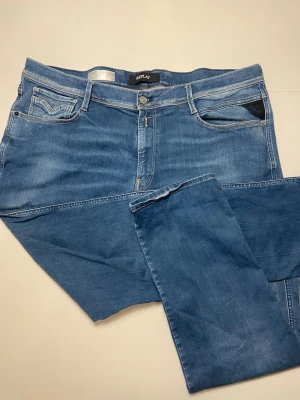 Replay Anbass blå jeans herr 44/32 - Säljer ett par snygga Replay Anbass jeans i klassisk blå tvätt. Modellen har normal passform och raka ben, med fem fickor och dragkedjegylf. Tillverkade i mjukt och stretchigt jeansmaterial för extra komfort. Perfekta till vardagslooken.