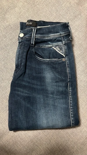 Replay Hyperflex Anbass jeans blå - Säljer ett par Replay Hyperflex Anbass jeans i mörkblå tvätt med snygga slitningar/fade. Modellen har slim fit, klassiska fem fickor och vita kontrastsömmar som ger en clean look. Stretchigt och riktigt bekvämt material med premiumkänsla – perfekta för en modern och stilren outfit.  Storlek: W29 L32 Skick: Bra skick Skickas samma dag vid snabb affär 📦⚡️