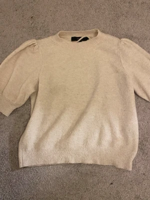 Beige stickad tröja Vero Moda S - Säljer en beige stickad tröja från Vero Moda i storlek S. Tröjan har puffiga korta ärmar och ribbade muddar vid hals, ärmslut och nederkant. Enkel och stilren modell som är lätt att matcha till olika outfits. Pris kan diskuteras vid snabbt köp💕