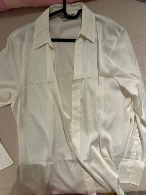 Vit satinliknande skjorta i M - Säljer en stilren vit skjorta i satinliknande material med klassisk krage och långa ärmar. Ett bra material, använde knappt. Bara 2 gånger. 