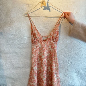 Blommig sommarklänning  - Supersöt blommig sommarklänning med smala axelband, v-ringning och korsas i ryggen. Passar en xs/s🩷🩷