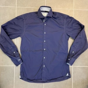 Blå skjorta från Stenströms - Snygg blå skjorta från Stenströms i fitted body-modell. Tillverkad i twofold super cotton med vita knappar och mönstrad insida på kragen. Perfekt för dig som gillar stilrena och klassiska plagg med en twist. Storlek 39