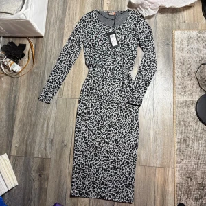 Leopardmönstrad långklänning från ONLY - Säljer en gråsvart långklänning från ONLY med leopardmönster. Klänningen har rund halsringning och långa ärmar. Materialet är mjukt och stretchigt, perfekt för dig som gillar att sticka ut lite extra.