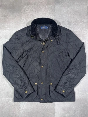 Ralph Lauren quilted jacka - Säljer en Ralph Lauren quilted jacka i stilren svart färg. 🧵 Märke: Ralph Lauren 👕 Storlek: Medium 🎨 Färg: Svart 📌 Design: Quilted / vadderad jacka 📍 Skick: Mycket bra, se bilder!  Beskrivning: • Tidlös och elegant quilted-design från Ralph Lauren • Lätt vadderad – perfekt för vår, höst och mild vinter • Bekväm passform med stilrena detaljer • Dragkedja framtill för smidig användning • Inga fläckar, noppor eller skador (kontrollera bilder) • Lätt att matcha med jeans, chinos eller mer uppklädda 