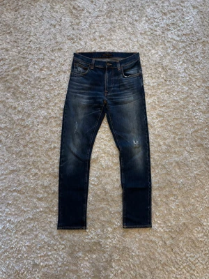Nudie jeans Lean Dean distressed vintage denim - Riktigt snygga blå jeans från nudie men snygg fade o snygga slitningar. De är använda men i gott skick utan några olagade hål! Storlek W29 L32. Mått: Hela längden: 101 cm Innerben: 76 cm Midja: 40 cm Benöppning: 17 cm