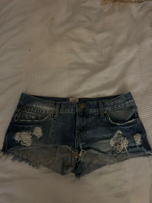 Blå slitna jeansshorts River Island - Säljer ett par blå jeansshorts från River Island med slitna detaljer och fransig. Skulle säga att det passar XS/XXS. Perfekta till sommaren för en avslappnad och trendig look.