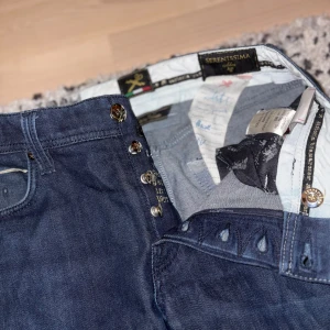 Tramarossa jeans Leonardo - Snygga mörkblå jeans från Tramarossa, ett klassiskt italienskt märke med bra kvalite. Modell: Leonardo och strl 32. Jätte bra skick utöver litet slitage på höger ficka (se bild 5)även ett sådant slitage på nedersidan av högerben, men de ser bara ut som design. Ny pris: ~3500. Hör av dig vid frågor. 