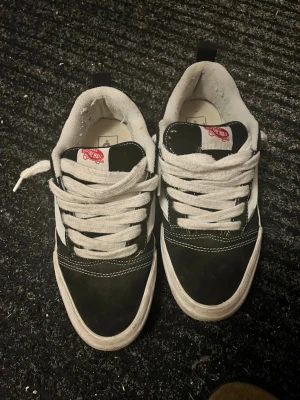 Svarta och vita Vans Old Skool sneakers - Klassiska Vans Old Skool sneakers i svart och vitt med den ikoniska vita sidoremsan. Skorna har vit sula, snörning och detaljer i mocka och canvas. Perfekta för dig som gillar streetstyle och skatekänsla. Snygga och tidlösa sneakers som passar till det mesta.