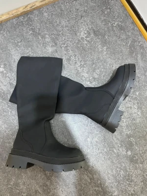 Svarta chunky stövlar med platåsula - Säljer ett par svarta höga stövlar med chunky platåsula och grovt mönstrad yttersula.. Perfekta för dig som vill ha en snygg look till hösten eller vintern.